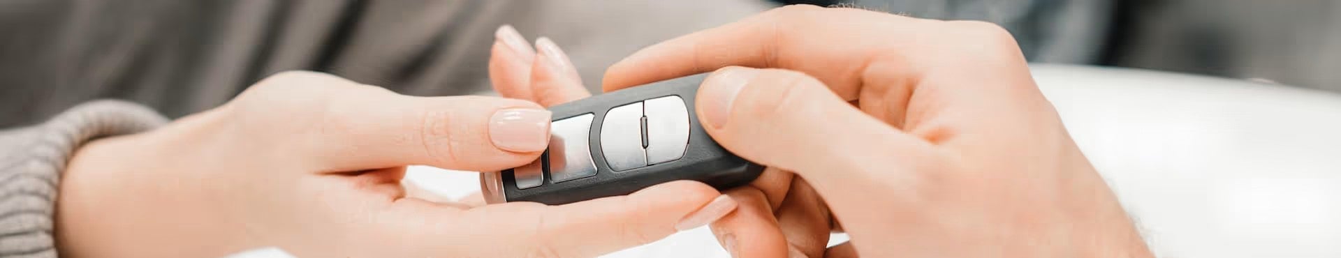 Close-up of a car key fob being handed from one person to another